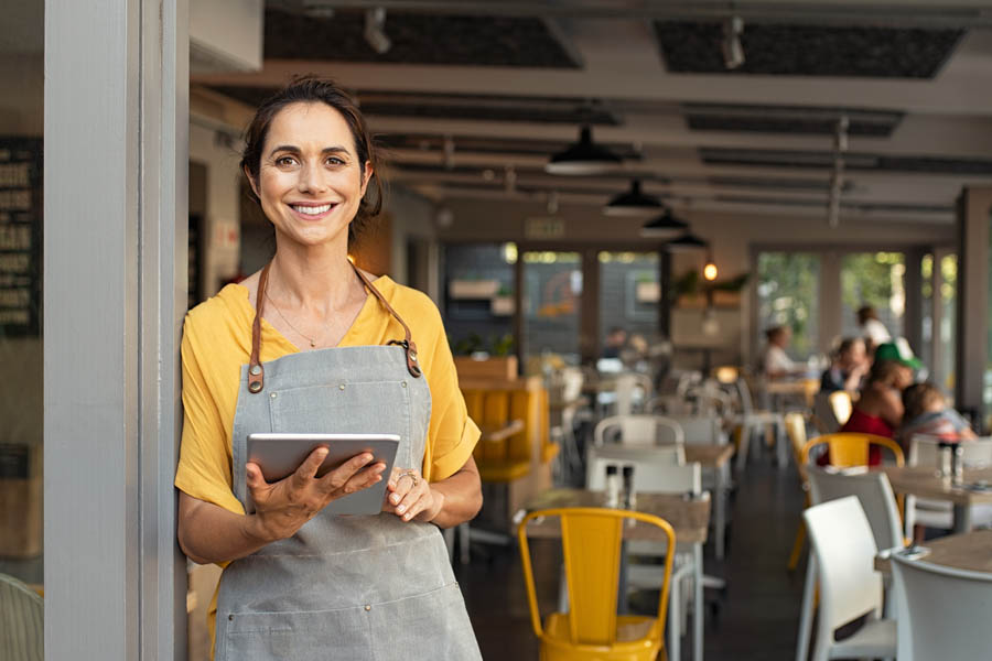 Specialized Business Insurance - Woman Using a Tablet in the Front of Her Restaurant